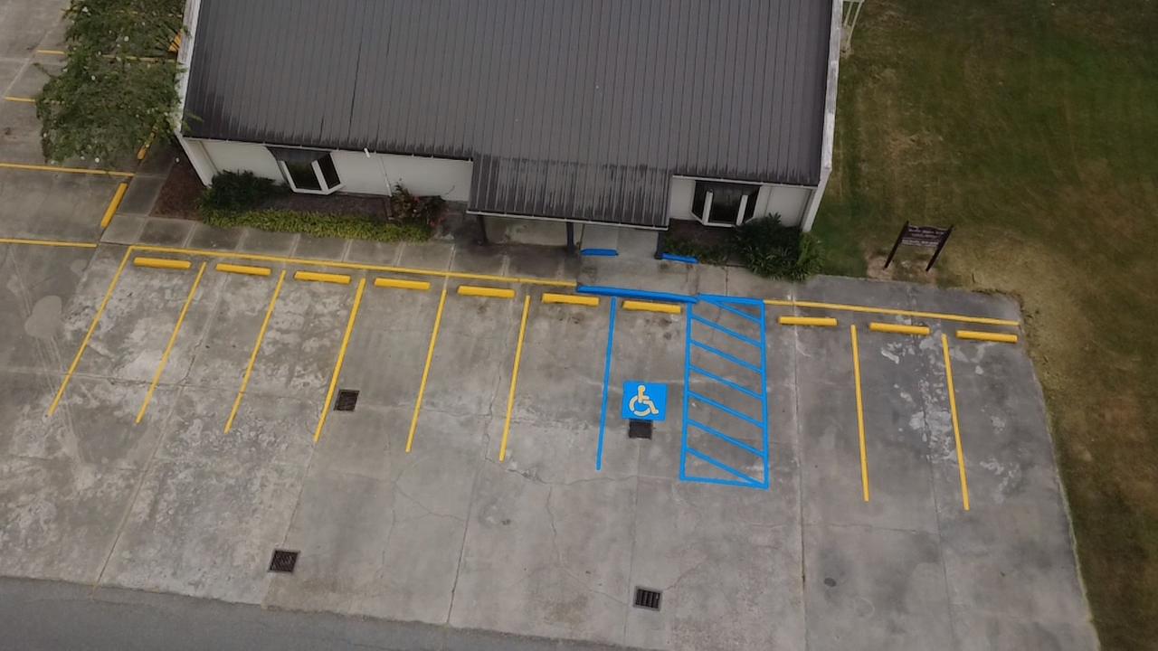 Overhead view of a blue accessible parking space with a crosshatched access aisle at a medical office in Eunice, LA