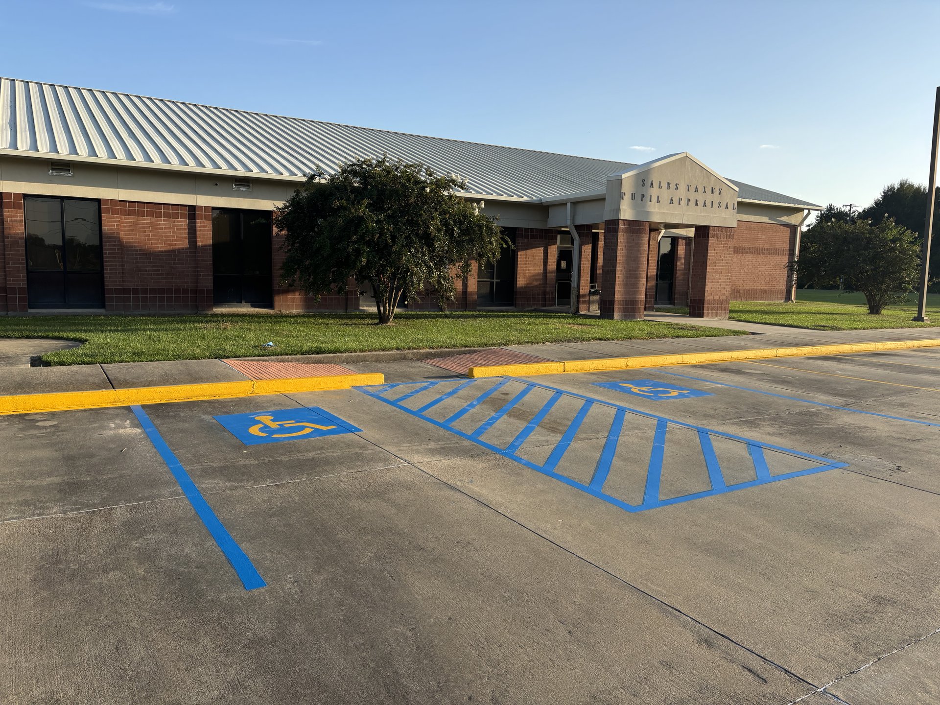 Freshly painted blue handicap parking space and access aisle striping in front of a Louisiana office building