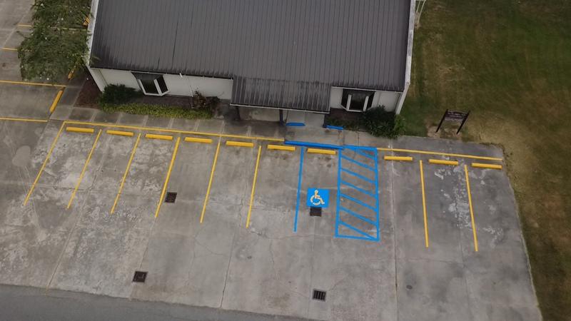 Overhead view of a blue accessible parking space with a crosshatched access aisle at a medical office in Eunice, LA